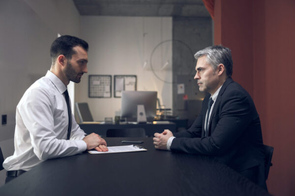 Abbildung: Mann sitzt am Tisch mit seinem Anwalt