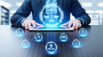 Abbildung: Mann sitzt am Tisch vor Laptop mit schwebenden Icons mit juristischer Symbolik